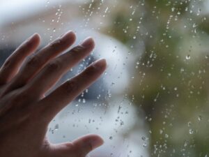 雨粒の窓に置かれた女性の手