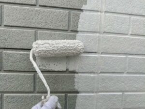 グレーのサイディングに真っ白な下塗り材を塗ってる様子