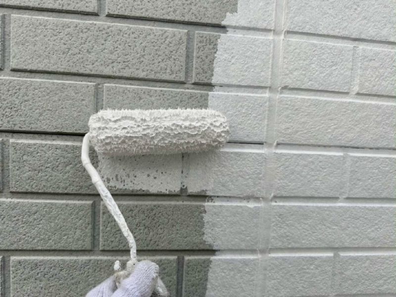 グレーのサイディングに真っ白な下塗り材を塗ってる様子