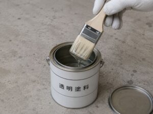透明塗料の缶に刷毛を浸す手
