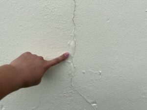 外壁のひび割れを指で指摘
